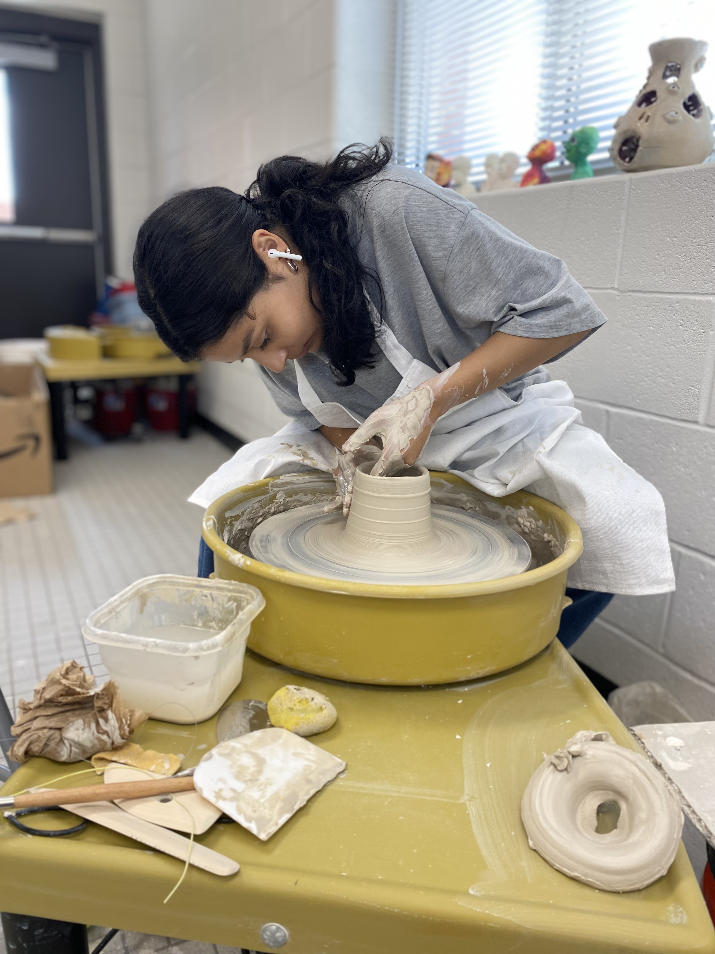 girl throwing clay on a potter's wheel girl throwing clay on a potter's wheel